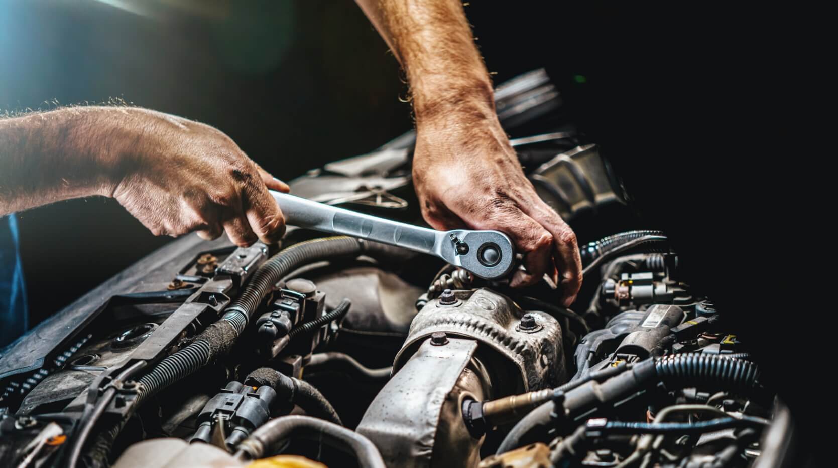 nextgen-hero NextGen service technician repairing loose hose under hood of vehicle.